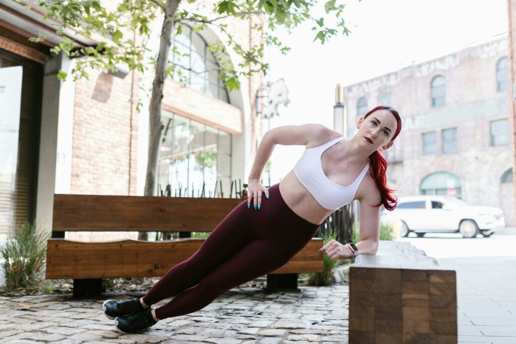 Fit woman doing side plank exercise against a bench.